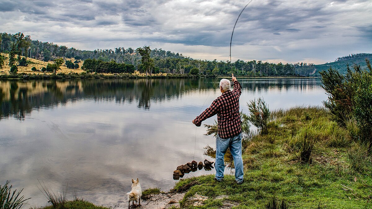 old man fly fishing at lake