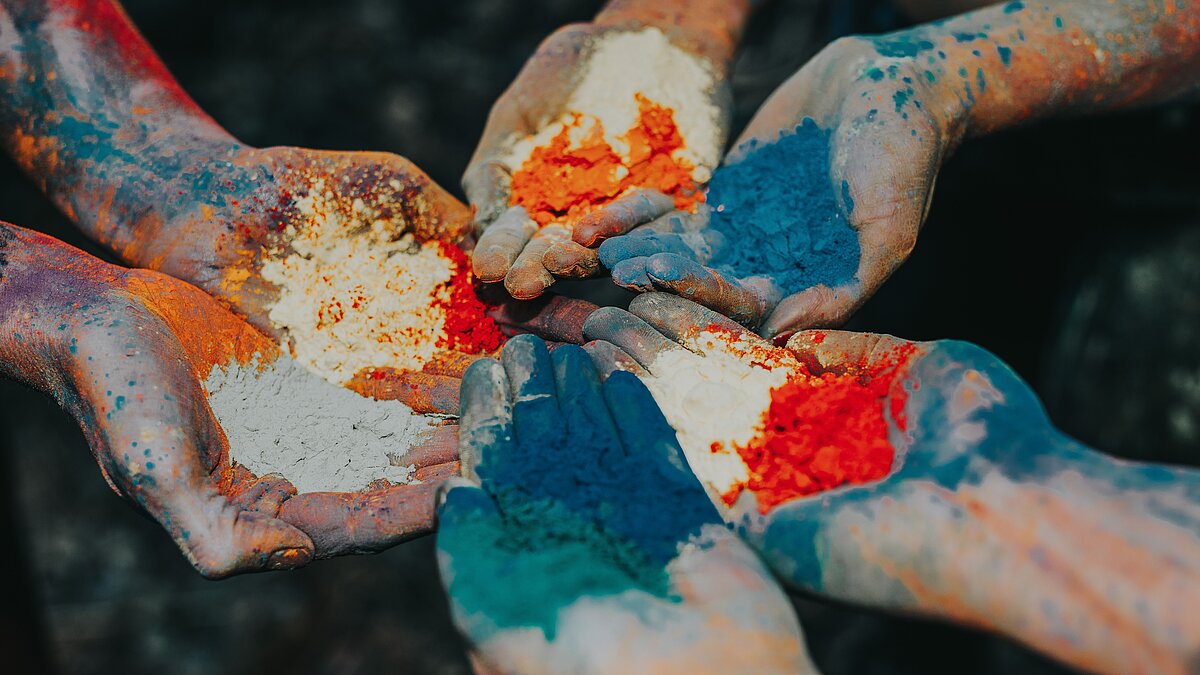 3 pairs of hands covered with coloured powder